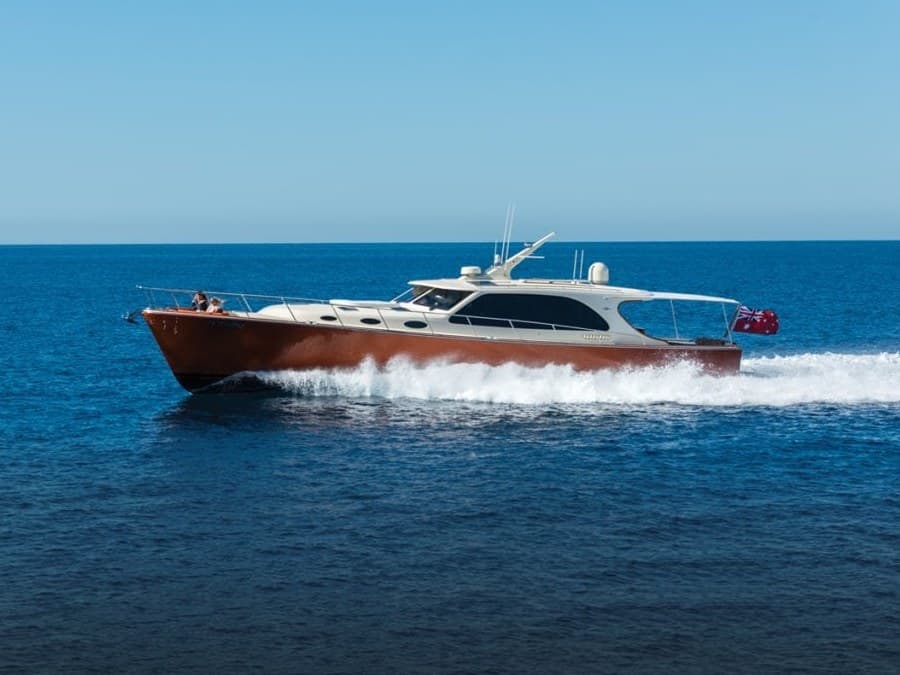 A downeast express cruiser with a varnished mahogany hull running flat in open water