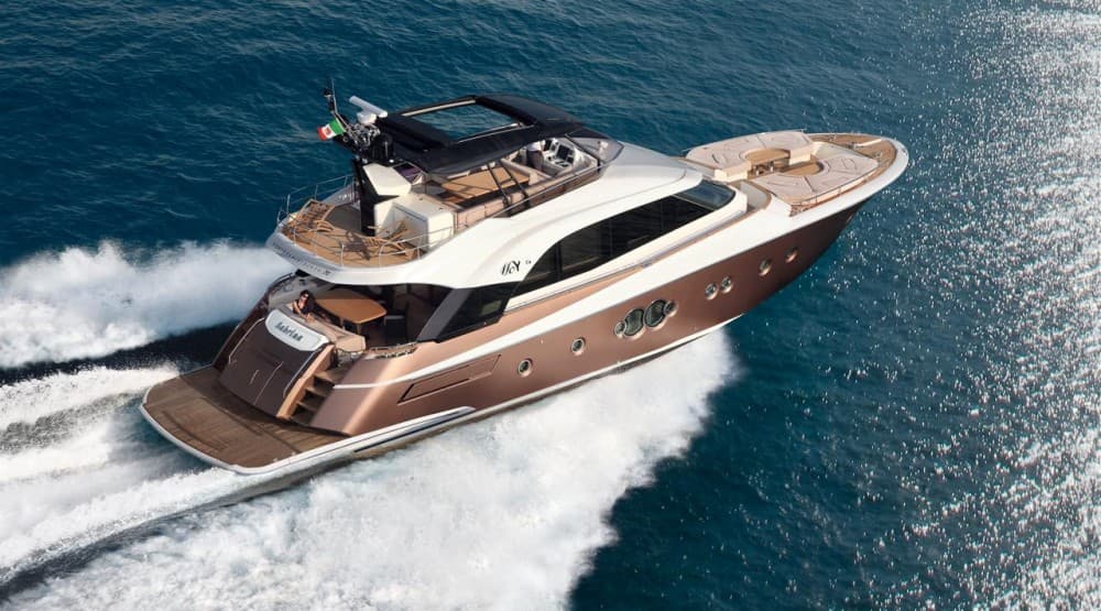 A flybridge motor yacht with a bronze hull running in open water, seen from above the starboard quarter