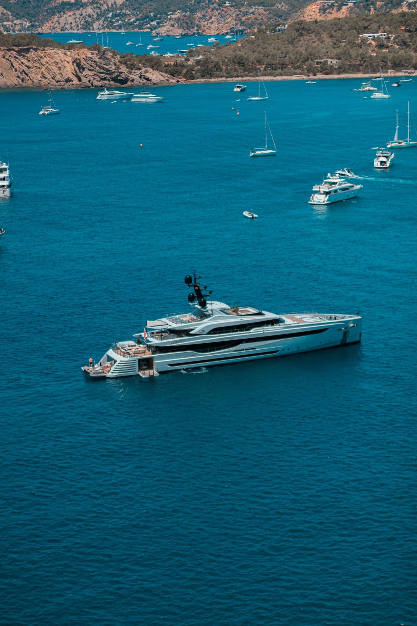 A superyacht at anchor off a Mediterranean coastline